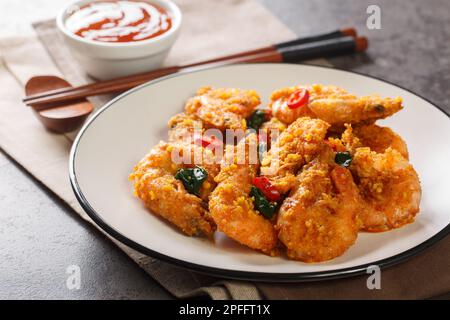 Des crevettes asiatiques sautées avec des jaunes d'œufs salés, des feuilles de curry et du piment gros plan dans une assiette sur la table. Horizontale Banque D'Images