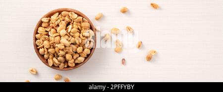 Grains de cacahuètes aromatisés épicés dans un bol sur fond de table blanc. Banque D'Images