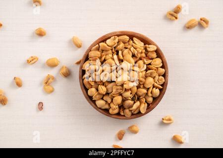 Grains de cacahuètes aromatisés épicés dans un bol sur fond de table blanc. Banque D'Images