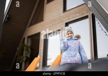 Petite fille sur la terrasse hors de la grille petite maison dans les montagnes. Banque D'Images