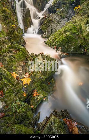Une longue exposition d'une cascade, encadrée par une colline verdoyante recouverte de mousse. Banque D'Images