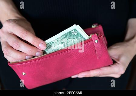 fille tient un portefeuille dans ses mains, shopping, dollars dans son sac à main, portefeuille plein de dollars Banque D'Images