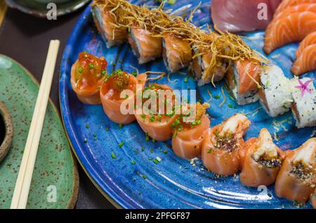 Mélange de différents sushis japonais sur une élégante assiette bleue. Banque D'Images