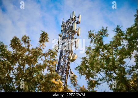 5G mât de l'émetteur contre le ciel bleu entre les arbres Banque D'Images