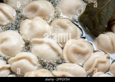 Cadre complet de boulettes dans de l'eau bouillante. Les boulettes sont bouillies dans une casserole d'eau bouillante et de feuilles de Laurier. Restauration rapide à la maison. Banque D'Images