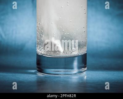 Gros plan avec un comprimé de vitamine C effervescente se dissolvant dans un verre d'eau Banque D'Images