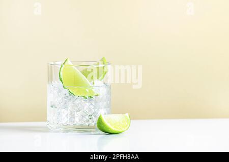 Cocktail alcoolisé TI punch avec rhum blanc, sirop de sucre et citron vert, boisson traditionnelle des Caraïbes. Arrière-plan beige, style minimaliste Banque D'Images