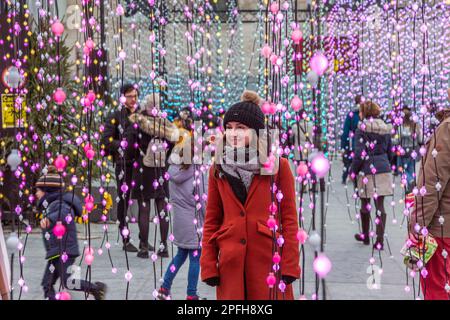 Jeux de lumière au Mont-des-Arts à Bruxelles, à l'occasion des illuminations de fin d'année. Jeune femme en robe rouge photographiée. Banque D'Images