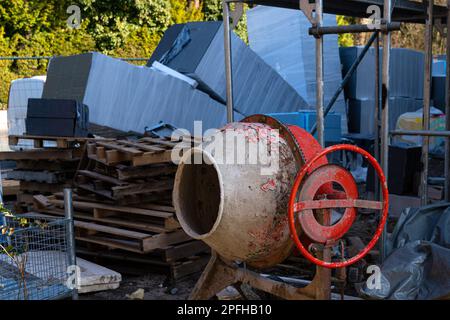 Un ancien mélangeur de béton de sorbde sur un chantier de construction. Les balles contenant des matériaux de construction se trouvent dans un tas. Gros plan. Banque D'Images