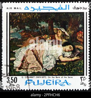 FUJEIRA - VERS 1968 : un timbre imprimé à Fujeira montre sur la rive de la Seine, peinture de Gustave Courbet (1819-1877), peintre français, vers 1968 Banque D'Images