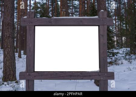 Panneau blanc vide avec un cadre en bois dans la forêt en hiver. Banque D'Images