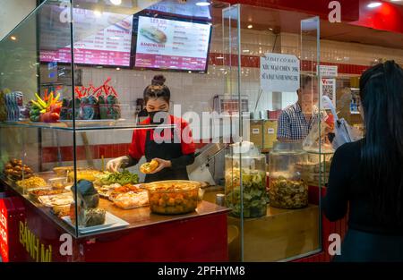 Une jeune femme assistant dans une boulangerie prépare un sandwich traditionnel vietnamien 'Banh mi' à Dalat, Vietnam. Banque D'Images