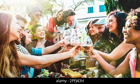 Groupe de personnes toaster le vin rouge en s'amusant en plein air applaudirant au pique-nique barbecue - jeune ami appréciant l'été ensemble à la fête de jardin à côté Banque D'Images