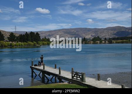 Deux personnes pêchent à partir d'une jetée au lac Dunstan, Cromwell, Central Otago. Le lac a été formé par le barrage de la centrale construit sur la rivière Clutha. Banque D'Images