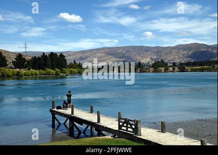 Deux personnes pêchent à partir d'une jetée au lac Dunstan, Cromwell, Central Otago. Le lac a été formé par le barrage de la centrale construit sur la rivière Clutha. Banque D'Images