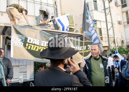 Bnei Brak, Israël. 16th mars 2023. Les résidents ultra-orthodoxes de Bnei Brak marchent à côté d'une protestation des soldats de la réserve israélienne contre la réforme judiciaire. Les soldats ont ouvert un « centre de recrutement » au service militaire des FDI dans le cadre d’un acte de protestation contre la révision judiciaire de la ville ultra-orthodoxe de Bnei Brak. Crédit : SOPA Images Limited/Alamy Live News Banque D'Images