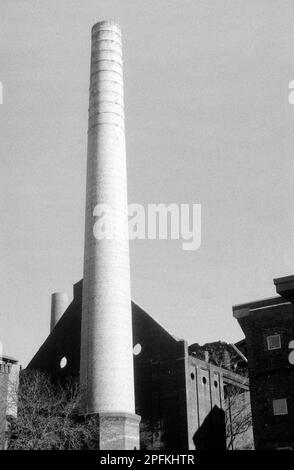 Le squelette d'un moulin à coton abandonné avec un énorme fumkestack atteignant vers le ciel derrière le centre d'accueil du parc national à Lowell, Massa Banque D'Images