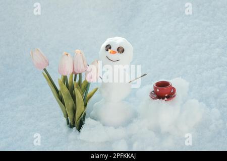 Bonjour printemps, bye hiver. Bonhomme de neige avec tasse à café. Bonhomme de neige avec fleurs. Banque D'Images