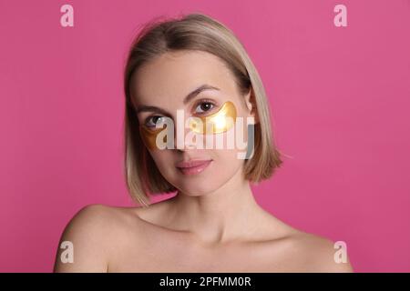 Belle jeune femme avec des taches sous les yeux sur fond rose Banque D'Images