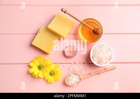 Cire d'abeille naturelle, baume à lèvres, miel, sel de mer et fleurs sur table en bois rose, plat Banque D'Images