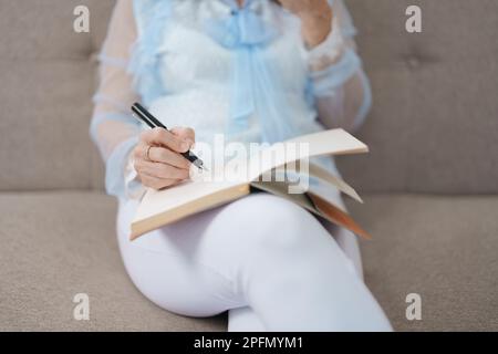 Portrait d'une femme asiatique âgée tenant un carnet à manger des collations et à boire du thé. Banque D'Images