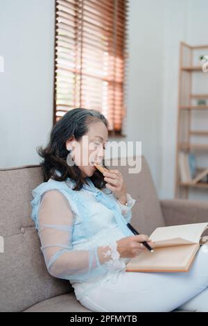 Portrait d'une femme asiatique âgée tenant un carnet à manger des collations et à boire du thé. Banque D'Images