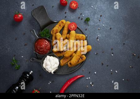 Bâtonnets de fromage Mozzarella cuits avec sauce tartare et tomate rouge sur une assiette Banque D'Images