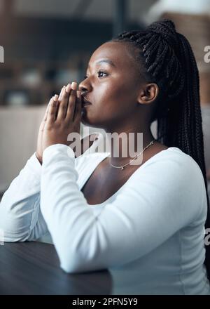 Il y a le pouvoir dans la prière. une jeune femme attirante s'agenouillant seule et priant dans sa maison. Banque D'Images