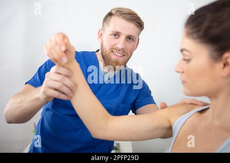 un physiothérapeute handsome qui traite l'épaule des patients Banque D'Images