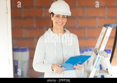 femme ingénieur civil tenant un casque de sécurité muni d'un presse-papiers Banque D'Images