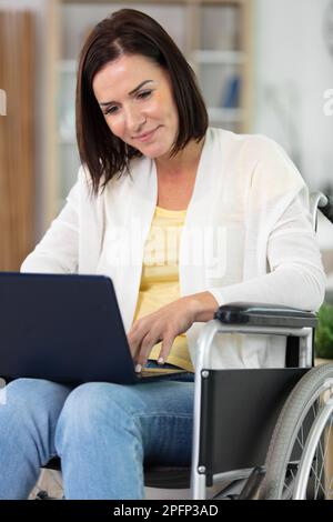 femme d'affaires confiante et heureuse travaillant en fauteuil roulant au bureau Banque D'Images