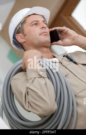 vue à angle bas du travailleur de la construction à l'aide d'un téléphone Banque D'Images