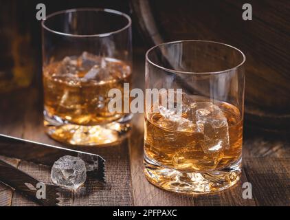Deux verres de whisky avec glace sur fond rustique en bois Banque D'Images