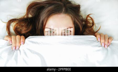 Femme au lit. La fille cache son visage sous les couvertures.concept de sommeil sain, insomnie, zone de confort Banque D'Images