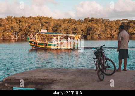 Valentica, Bahia, Brésil - 09 septembre 2022 : bateau naviguant sur la rivière una en fin d'après-midi tout en pêchant à la maison sur la rive. Ville de Valenca, Banque D'Images