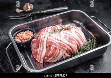 Cuisson du pain de viande cru avec de la viande de bœuf hachée et du bacon dans un plateau en acier, pain de viande frais. Arrière-plan noir. Vue de dessus. Banque D'Images