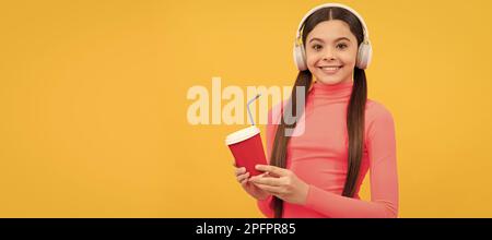 essayez. gamin joyeux avec une tasse à café à emporter avec un casque. Bonjour. Affiche horizontale de visage enfant isolé, en-tête de bannière, espace de copie. Banque D'Images