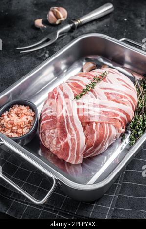 Cuisson du pain de viande cru avec de la viande de bœuf hachée et du bacon dans un plateau en acier, pain de viande frais. Arrière-plan noir. Vue de dessus. Banque D'Images