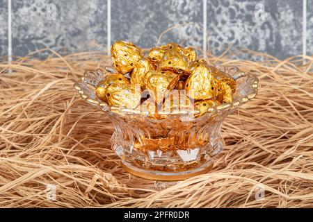 Chocolats emballés dans du papier d'aluminium dans des bonbons de luxe. Bonbons au chocolat dans une boîte dans un emballage en or. Banque D'Images