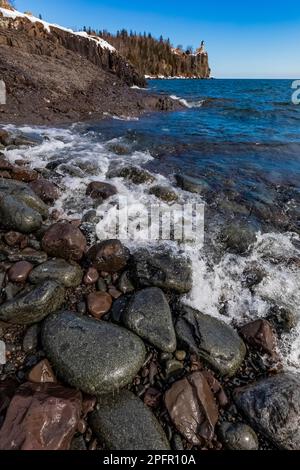 Vagues arrivant à terre sur la plage de galets sous le phare de Split Rock sur le lac supérieur, Minnesota, États-Unis Banque D'Images