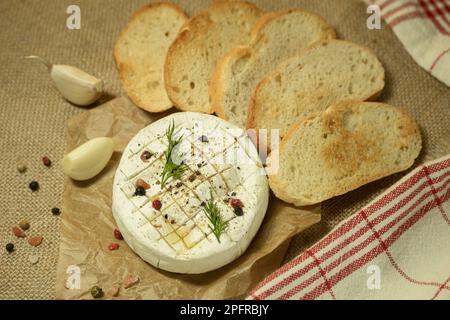 Camembert cuit au four avec épices sur papier de cuisson. Fromage frit maison sur une table rustique. bannière, menu, placer pour le texte, vue de dessus Banque D'Images