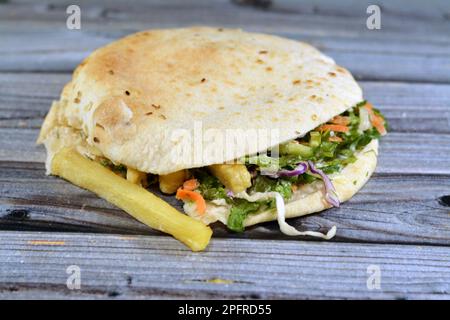 Pain syrien plat Shami rempli de frites et de salade verte, sandwich traditionnel égyptien avec des doigts de pommes de terre frits entouré de frais et croquant Banque D'Images