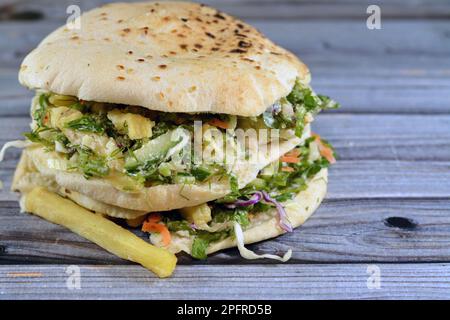 Pain syrien plat Shami rempli de frites et de salade verte, sandwich traditionnel égyptien avec des doigts de pommes de terre frits entouré de frais et croquant Banque D'Images