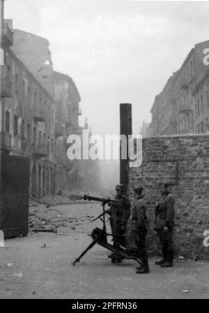 En janvier 1943, les nazis sont arrivés pour arrondir les Juifs du ghetto de Varsovie les Juifs, résolus au combattre, ont pris la SS avec des armes maison et primitives. Les défenseurs ont été exécutés ou déportés et la zone du ghetto a été systématiquement démolie. Le chef nazi, Jurgen Stroop, a publié un livre pour célébrer sa victoire. Ce livre , connu sous le nom de rapport Sroop, a été utilisé par les poursuites de Nuremberg. Cet événement est un lieu de rencontre comme le soulèvement du ghetto. Cette image montre des saisies de la police allemande avec une mitrailleuse lourde à la porte du ghetto. Banque D'Images