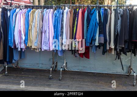 Chemises multicolores pour hommes sur le rail à l'entrée du magasin. Vintage Charity Fair Banque D'Images