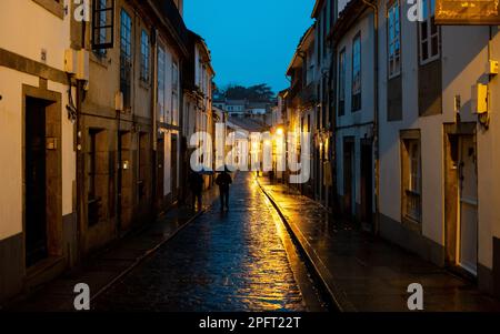 Les plazas baignés de pluie et les bâtiments historiques de Saint-Jacques-de-Compostelle, en Espagne, prennent une beauté étincelante sous la lueur des réverbères Banque D'Images