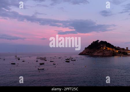 Le ciel devient rose et orange lorsque le soleil se couche sur Tossa de Mar, en Espagne, créant une vue pittoresque depuis la plage et le château Banque D'Images