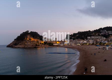 Le soleil se couche sur les sables dorés de Tossa de Mar, en Espagne, et diffuse une lumière chaude sur la plage Banque D'Images