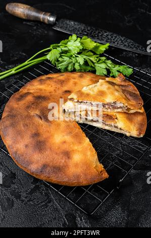 Tarte d'ossète cuite avec de la viande de boeuf et des herbes. Arrière-plan noir. Vue de dessus. Banque D'Images