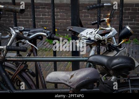 Vélos néerlandais typiques reposant contre une clôture devant un mur de pierre Banque D'Images